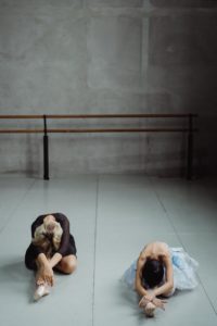 ballet dancers stretching body in studio
